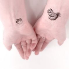 two people holding hands with small tattoos on their wrist and arm, one has a squirrel tattoo on the other hand