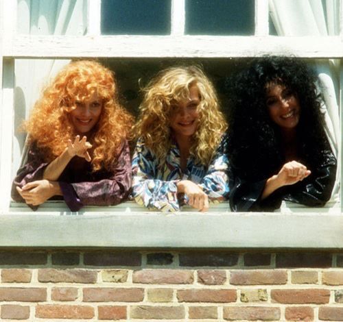 three women sitting on a window sill with their hands in the air and smiling