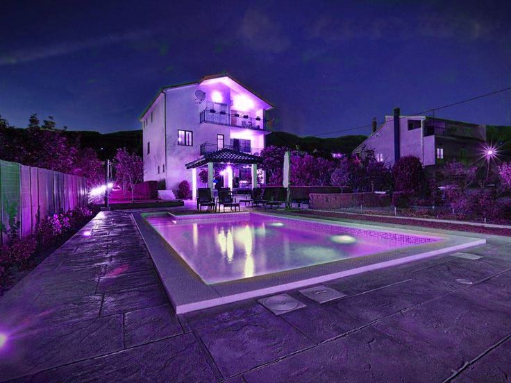 an outdoor swimming pool lit up with purple lights