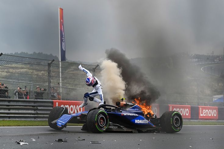 a man on top of a blue race car with flames coming out of the back