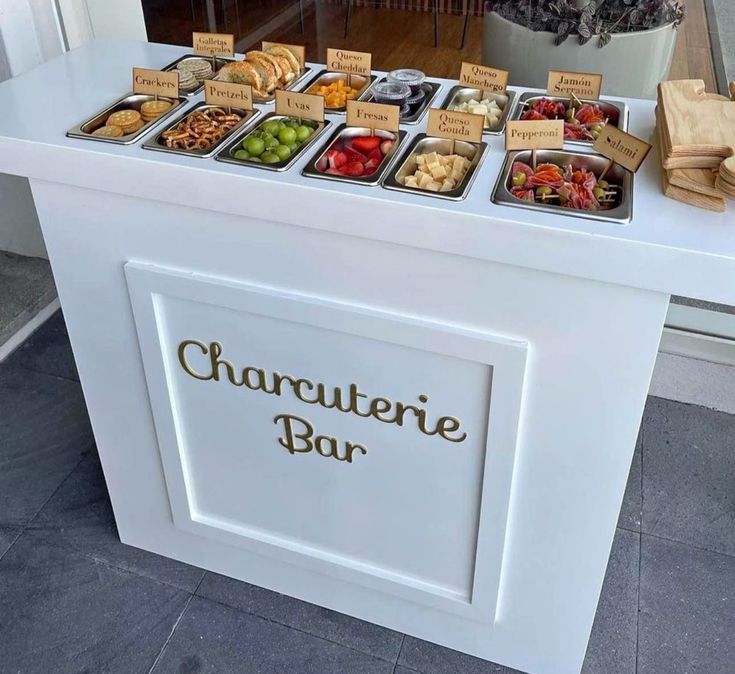 a table with many different types of food on it and the words charcuterie bar written in gold