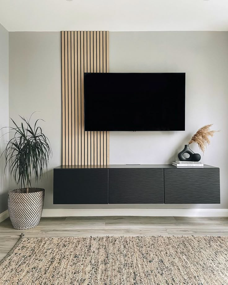 a flat screen tv mounted to the side of a wall next to a potted plant