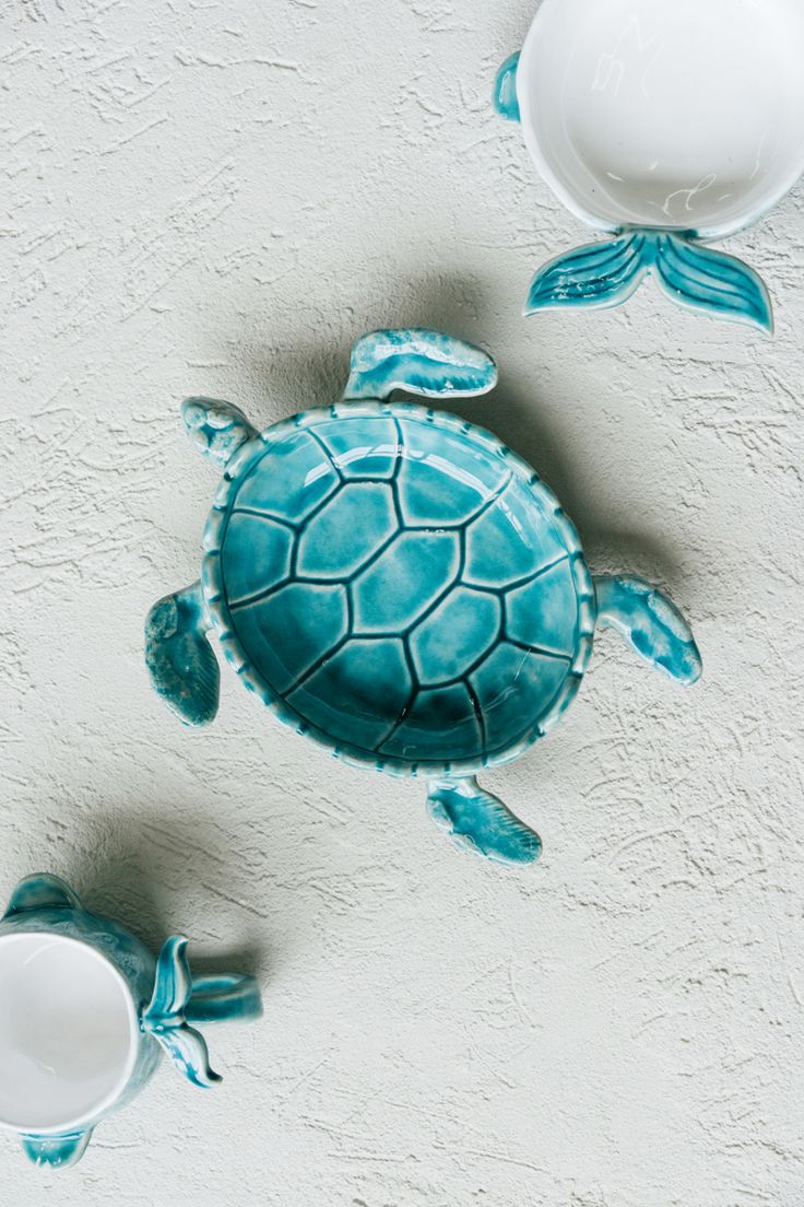 a blue turtle figurine sitting next to two bowls