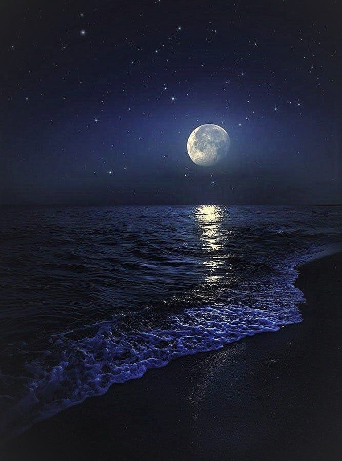 the moon is shining brightly over the water at night on the beach with waves crashing in front of it