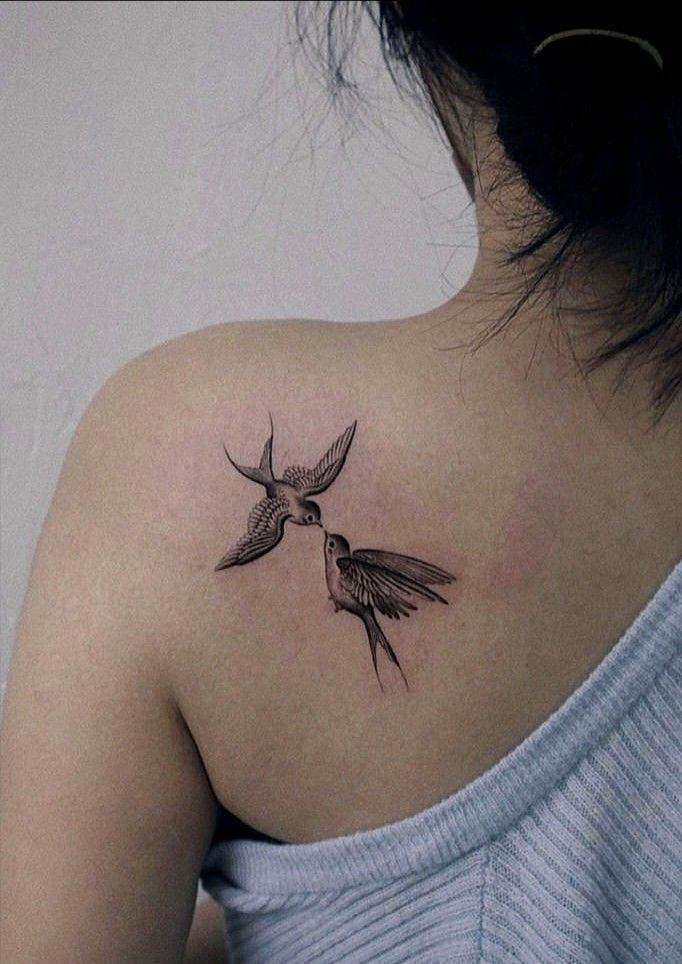 the back of a woman's shoulder with two birds on it