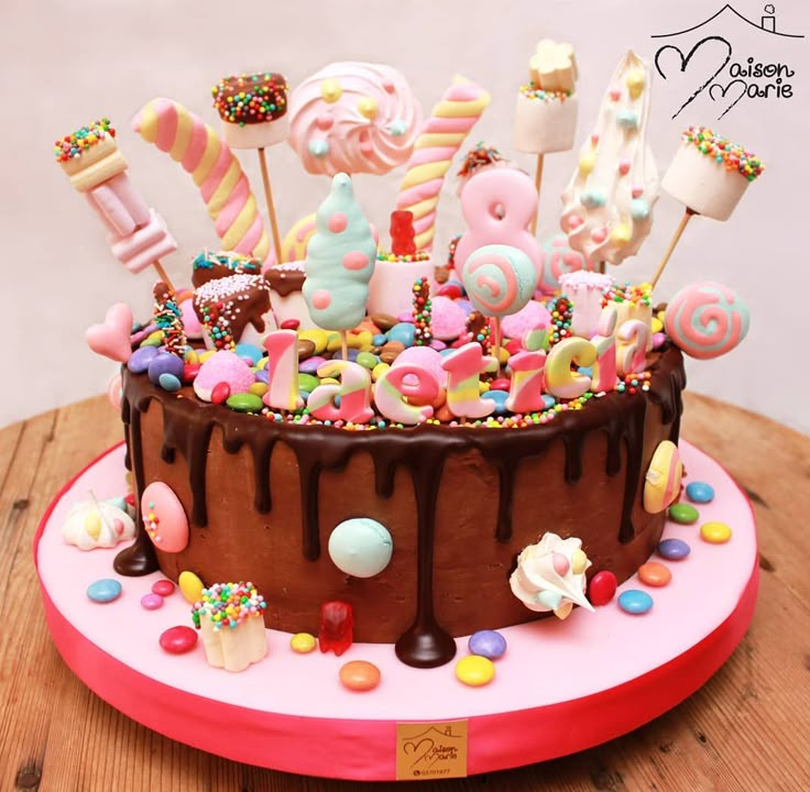 a chocolate cake covered in lots of candies and lollipops