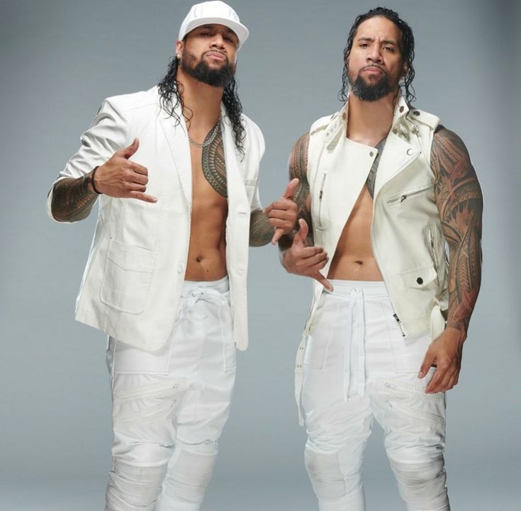 two men standing next to each other wearing white outfits and one has tattoos on his chest