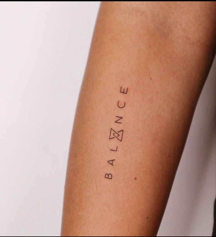 a woman's arm with the word balance tattooed on her left arm, in black ink