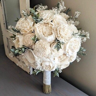 a bridal bouquet sitting on top of a table next to an old window sill