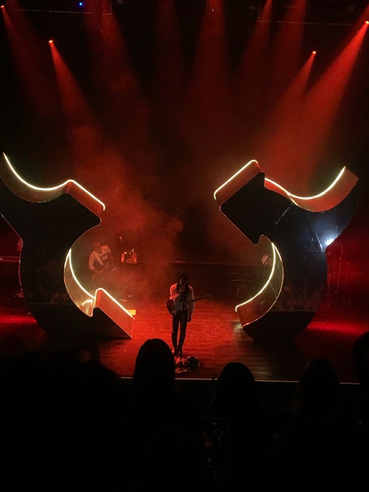 a man standing on top of a stage next to red lights