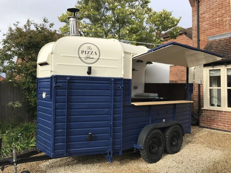 a blue and white food truck parked in front of a brick building