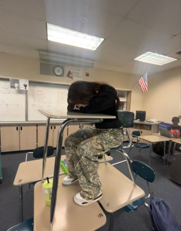 a woman sitting on top of a desk in a classroom