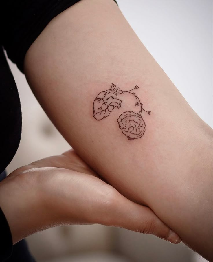 a person holding their arm with a tattoo on it's left side, which has two brain sections in the middle