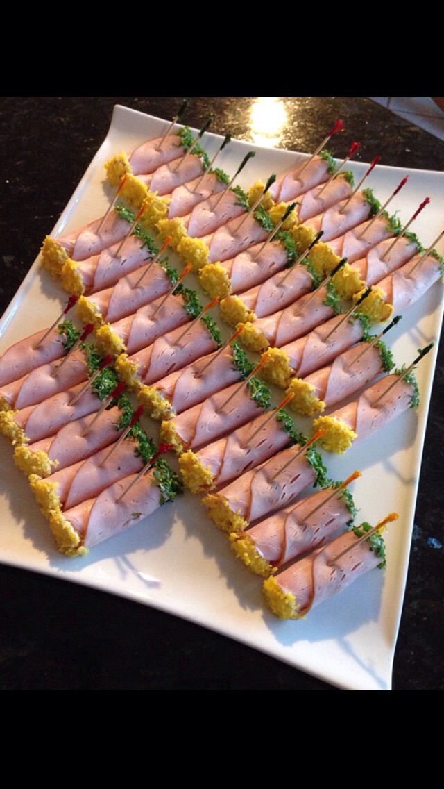 there are many small sandwiches on the white plate with green garnishes and toothpicks