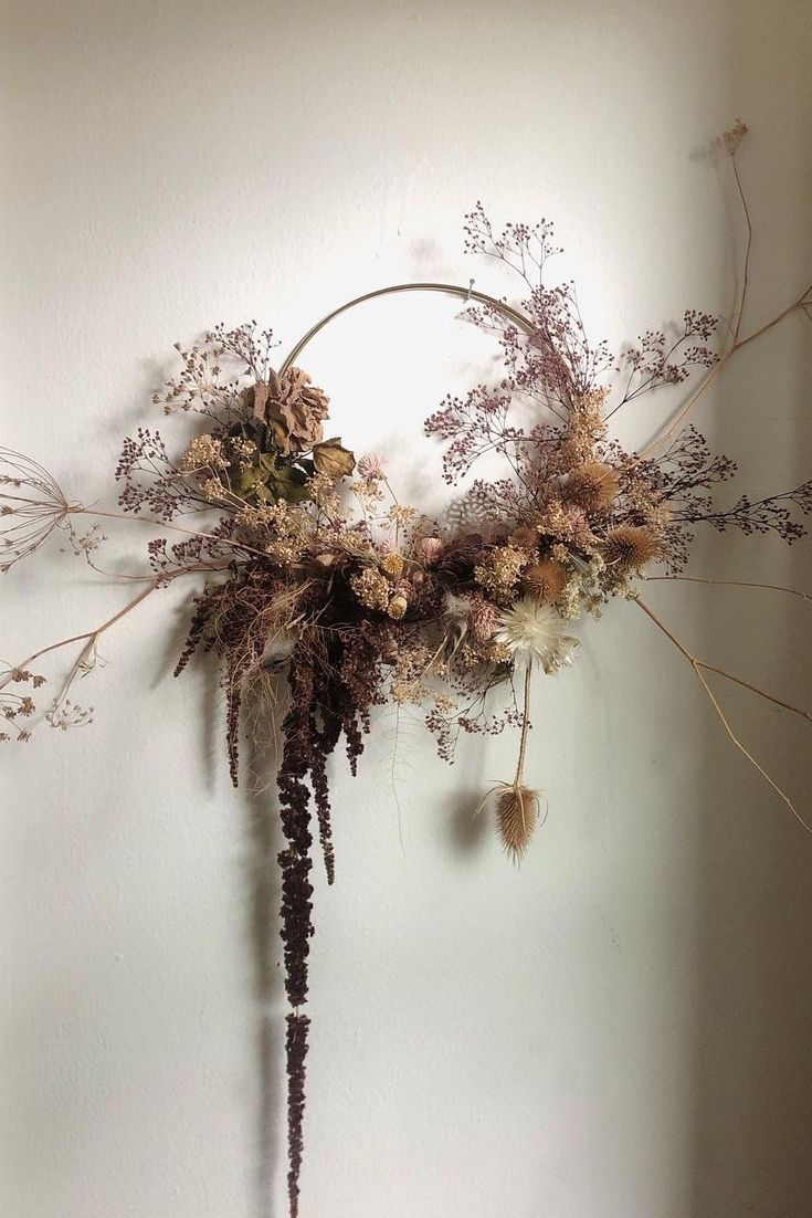 an arrangement of dried flowers hanging on a wall