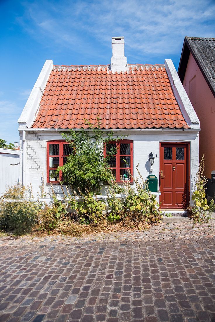 a white house with red shutters and a brick walkway leading to the front door