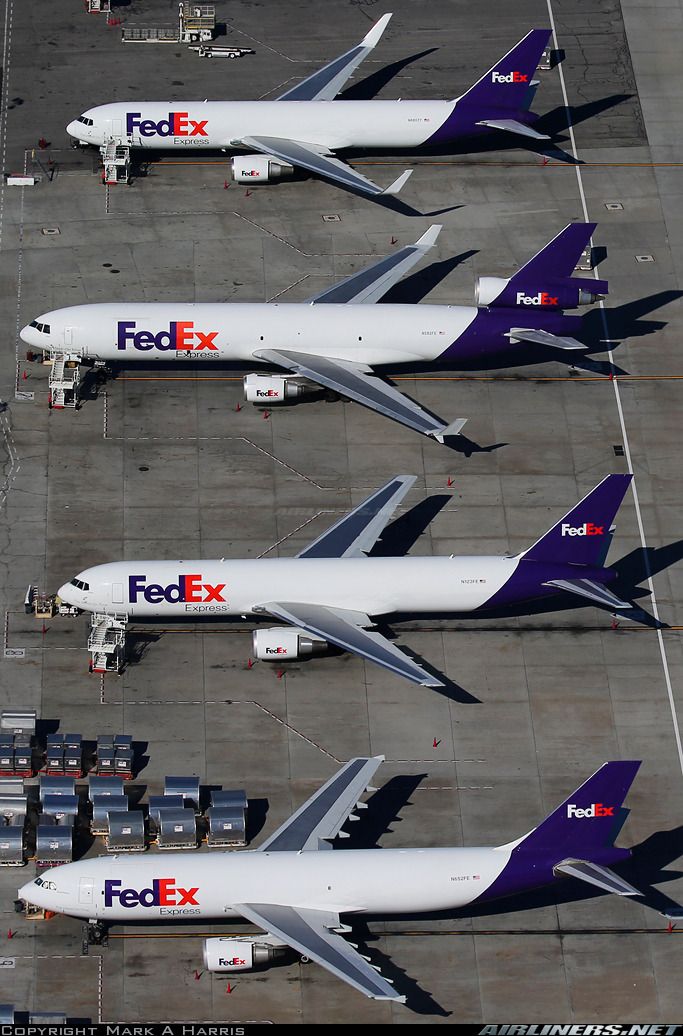 four fedex planes parked on the tarmac at an airport