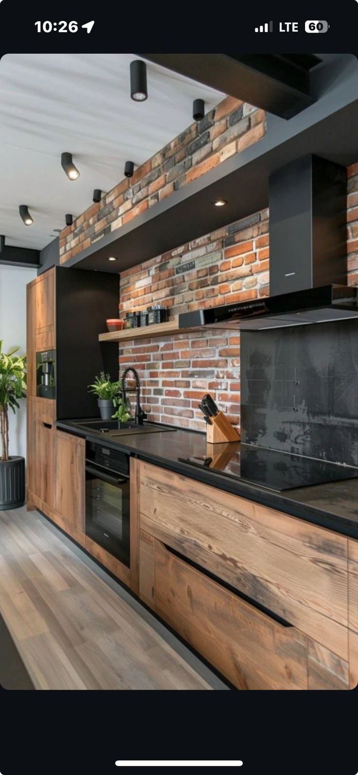 a kitchen with wooden cabinets and black counter tops, along with a brick wall in the background