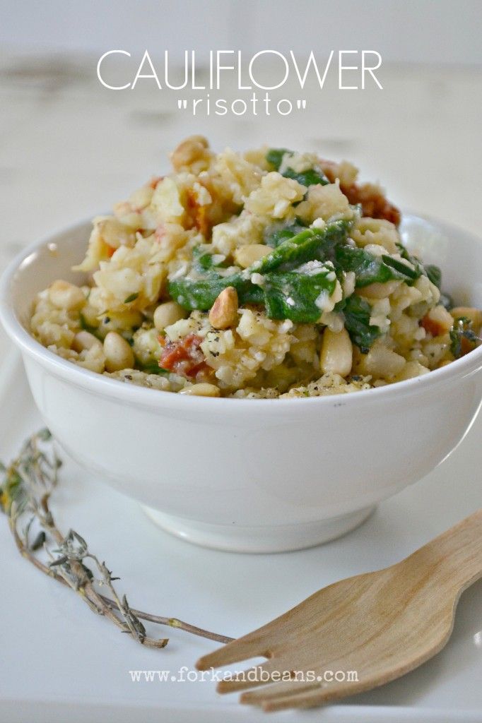 a white bowl filled with food sitting on top of a table next to a wooden spoon