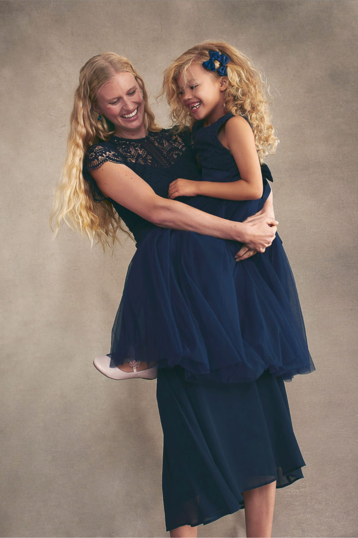 two women hugging each other in front of a gray background