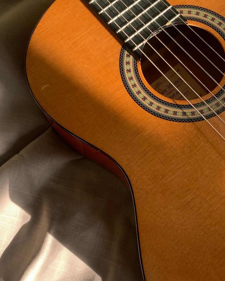 an acoustic guitar sitting on top of a bed