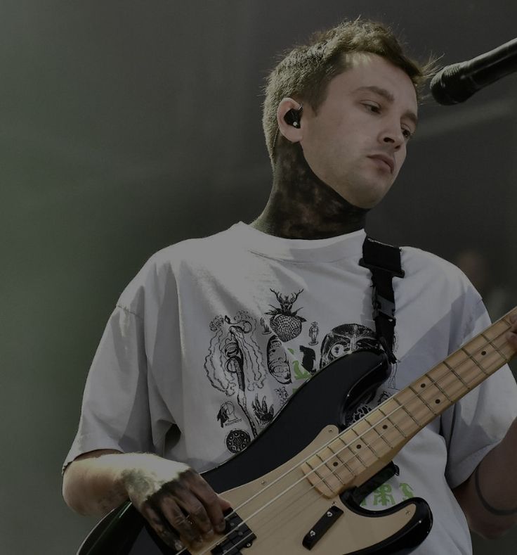 a man with tattoos on his face holding a bass guitar and singing into a microphone