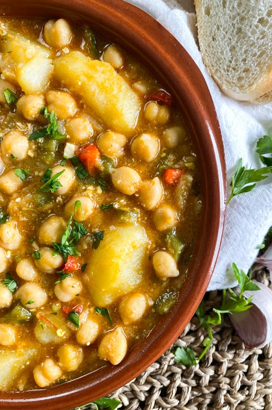 a brown bowl filled with stew next to bread