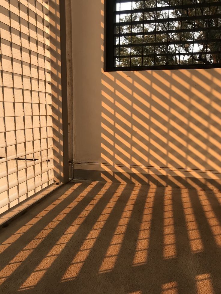 the sun is shining through blinds on a building's wall and onto an open window