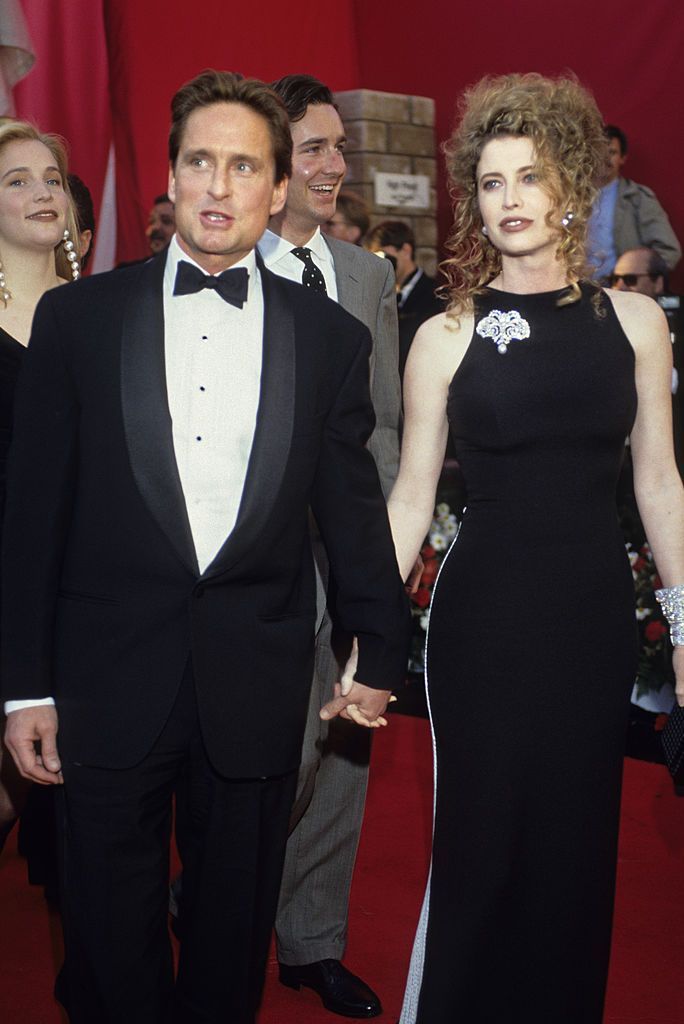 a man and woman in formal wear walk down the red carpet at an awards ceremony