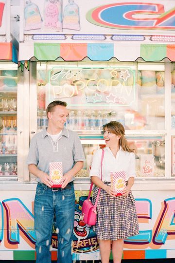 a man and woman standing in front of a candy shop