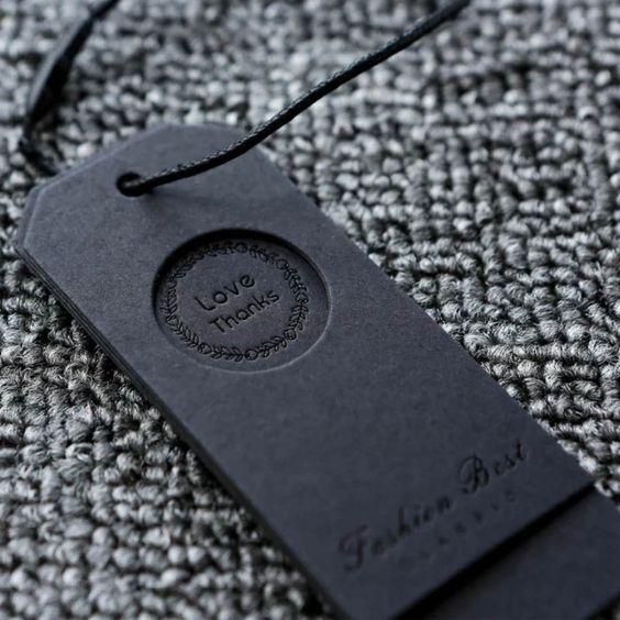 a black tag with the words love you on it sitting on a gray fabric background