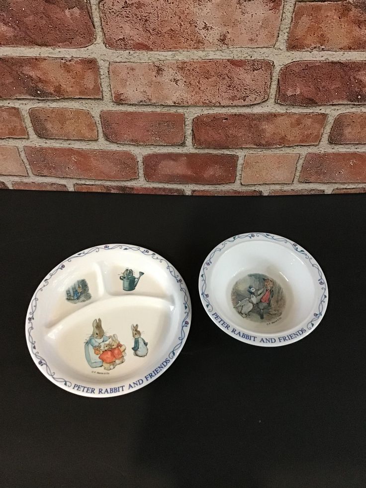 two white dishes sitting on top of a black table next to a brick wall,