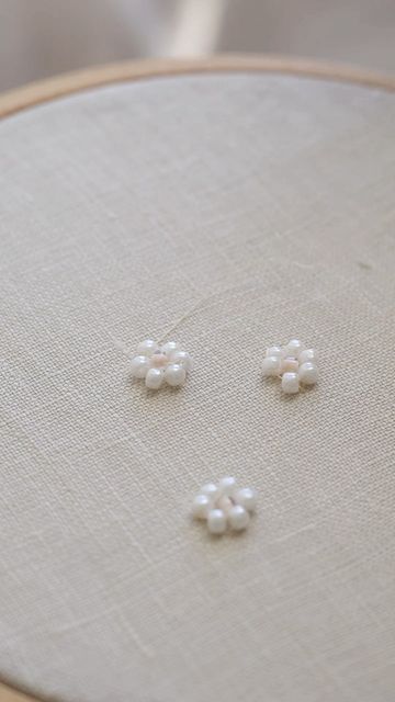 three white pearls are sitting on a piece of fabric in front of a wooden frame