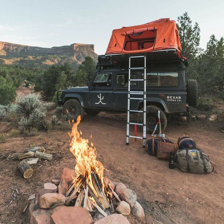 a truck is parked next to a campfire in the desert with an orange tarp on top