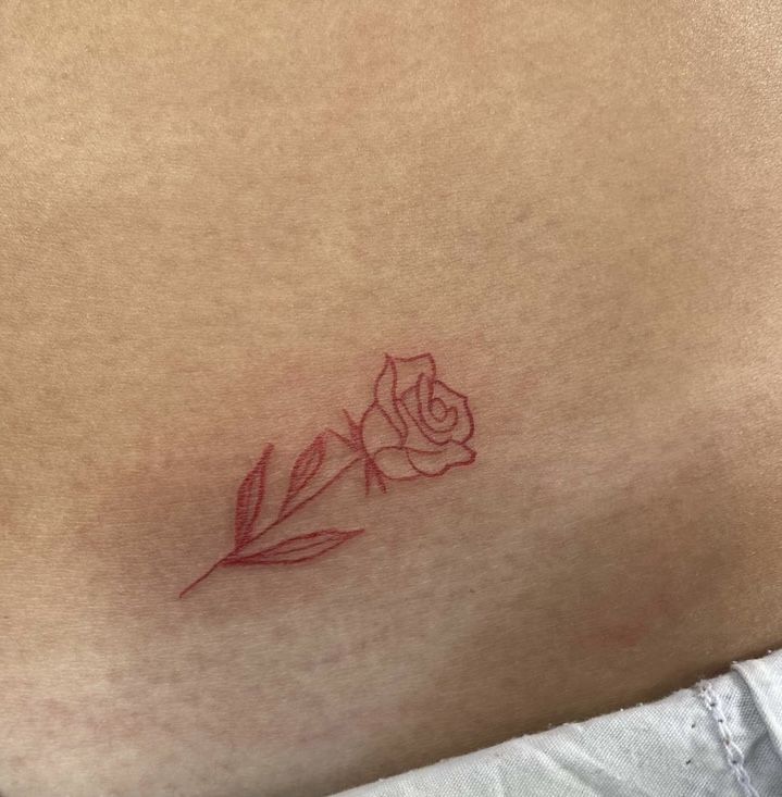 a small rose tattoo on the back of a woman's left shoulder and stomach