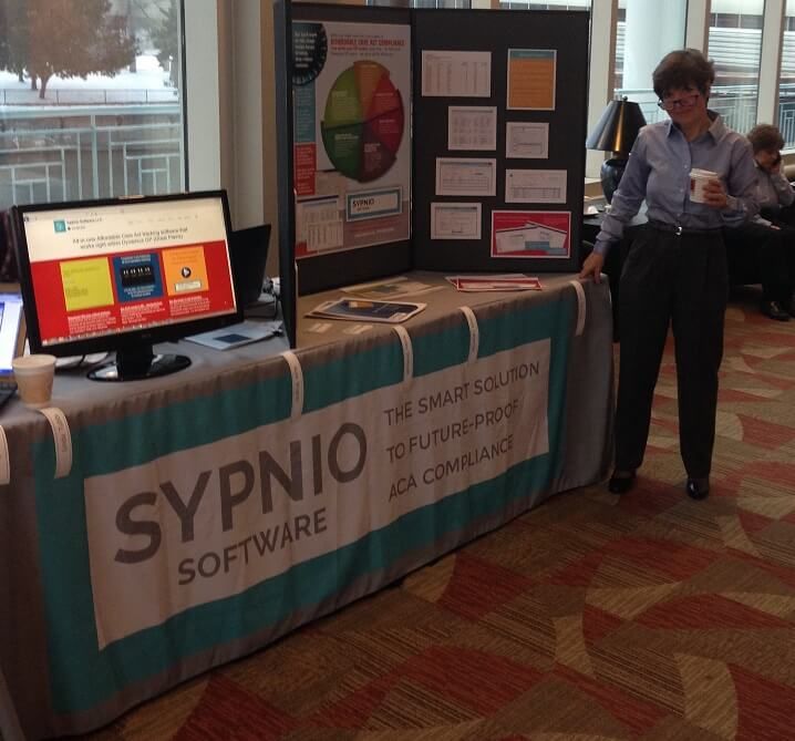 a man standing next to a table with a sign on it that says synio software