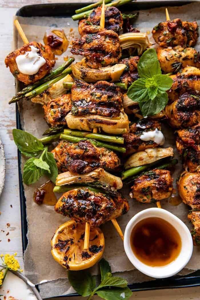 grilled chicken skewers with lemon wedges and mint garnishes