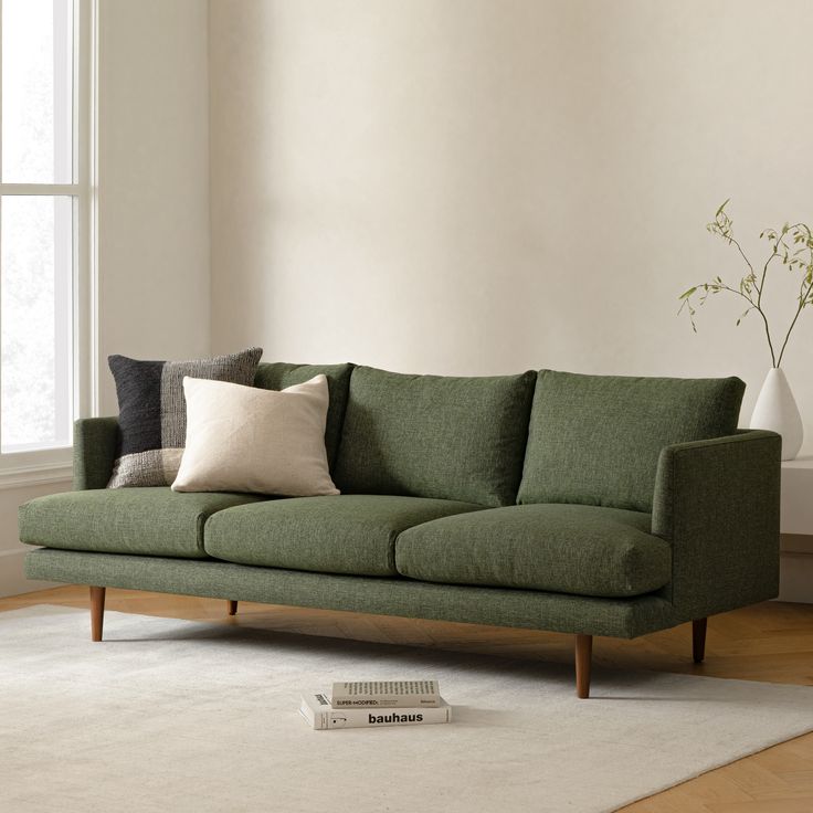 a green couch sitting on top of a white rug