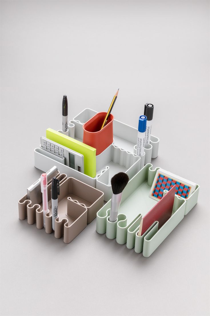 an assortment of office supplies including pens, pencils and makeup brushes are arranged on a white surface