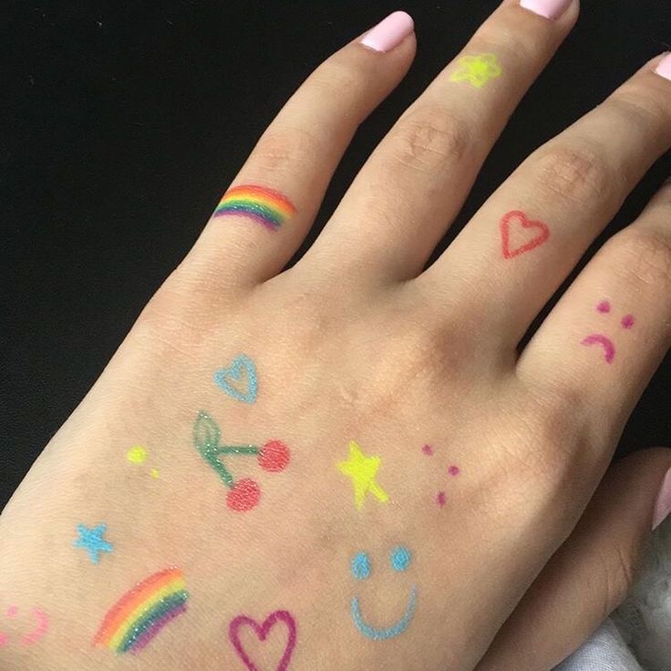 someone has their hand painted with rainbows and hearts