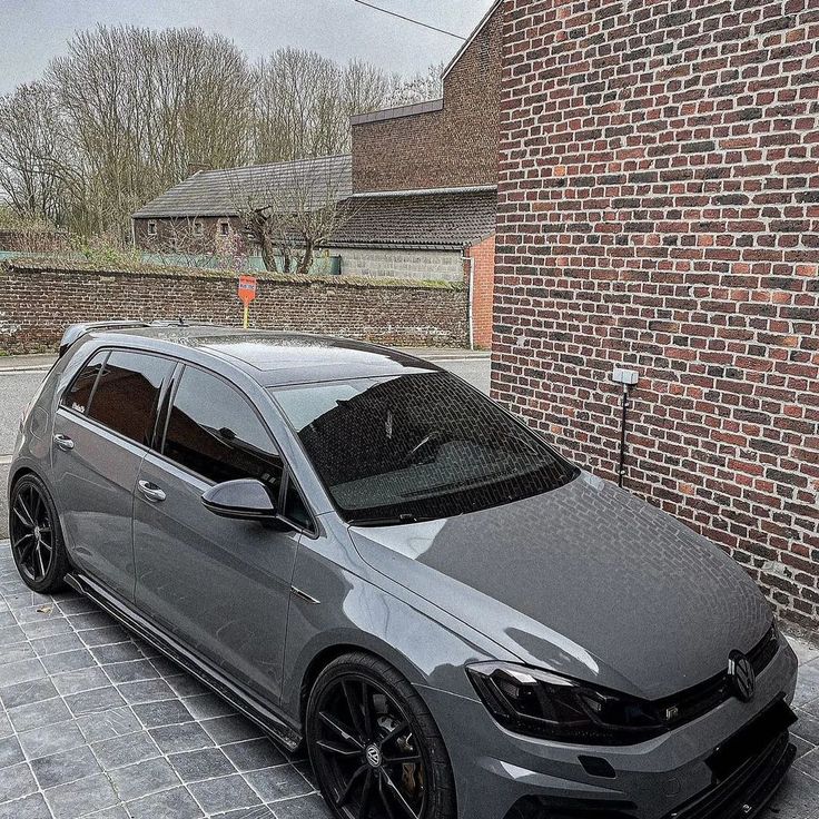 a grey car parked in front of a brick building on a cobblestone street