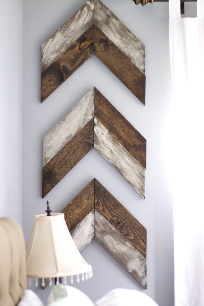 three wooden chevrons are mounted on the wall above a bed with a lamp