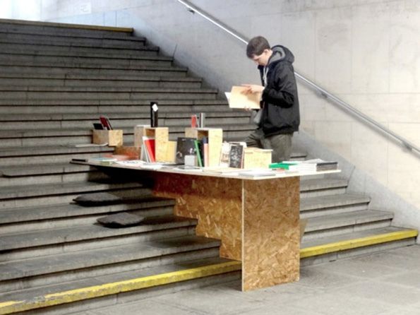 a man sitting at a table in front of a set of stairs holding a piece of paper