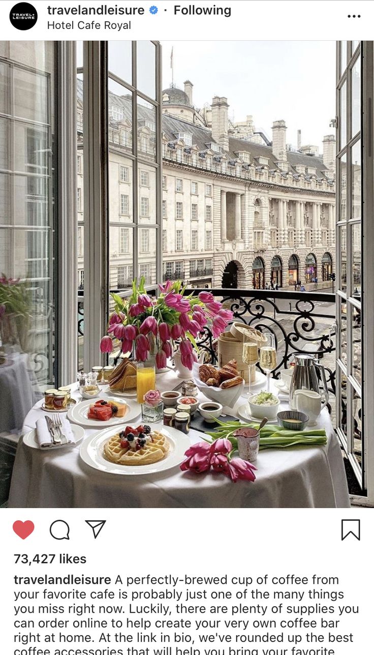 a table with food and drinks on it in front of a window overlooking the city