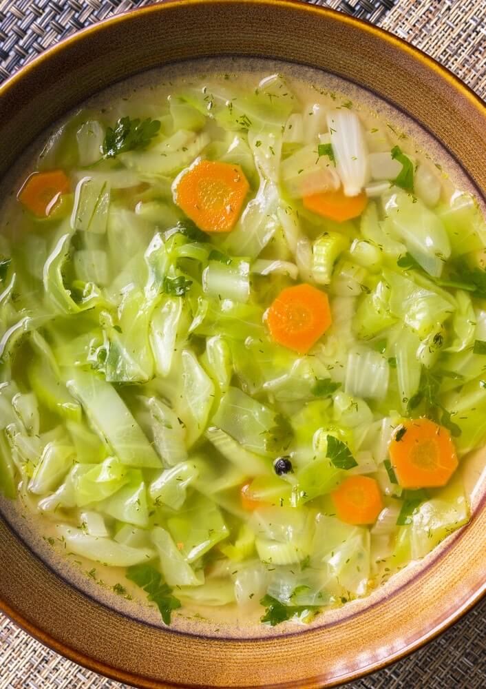 a bowl full of soup with carrots and celery in it on a table