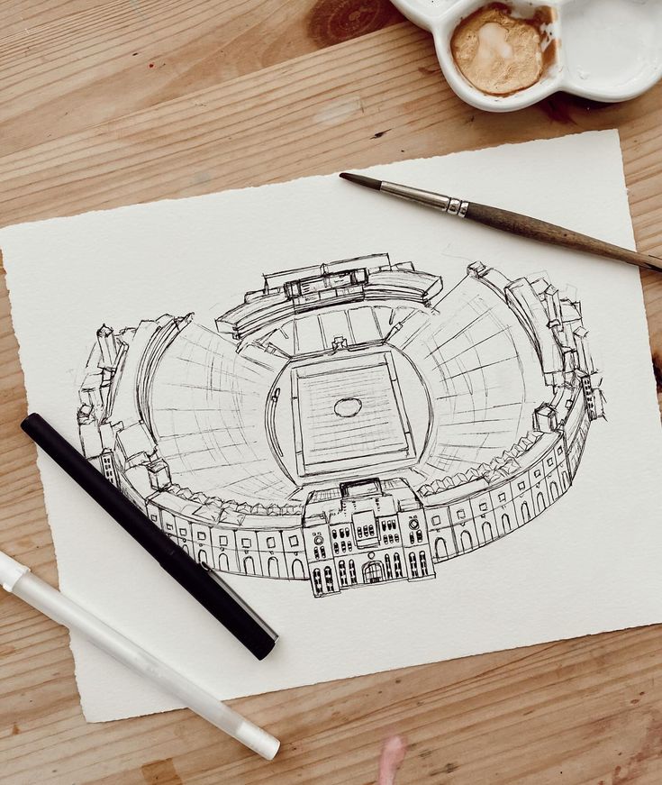 a drawing of a baseball stadium is on the table next to some markers and pens