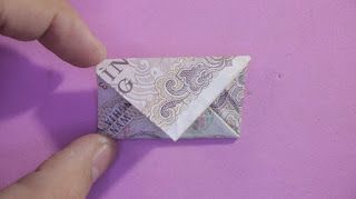 an origami envelope made out of money sitting on top of a purple surface