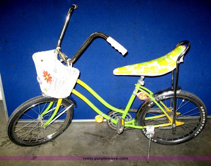 a green bicycle with a yellow seat and handlebars next to a blue wall