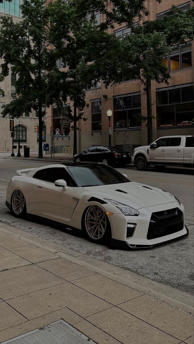 a white sports car parked in front of a tall building on the side of a street