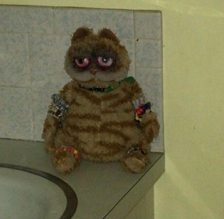 a stuffed animal sitting on top of a counter next to a sink in a bathroom